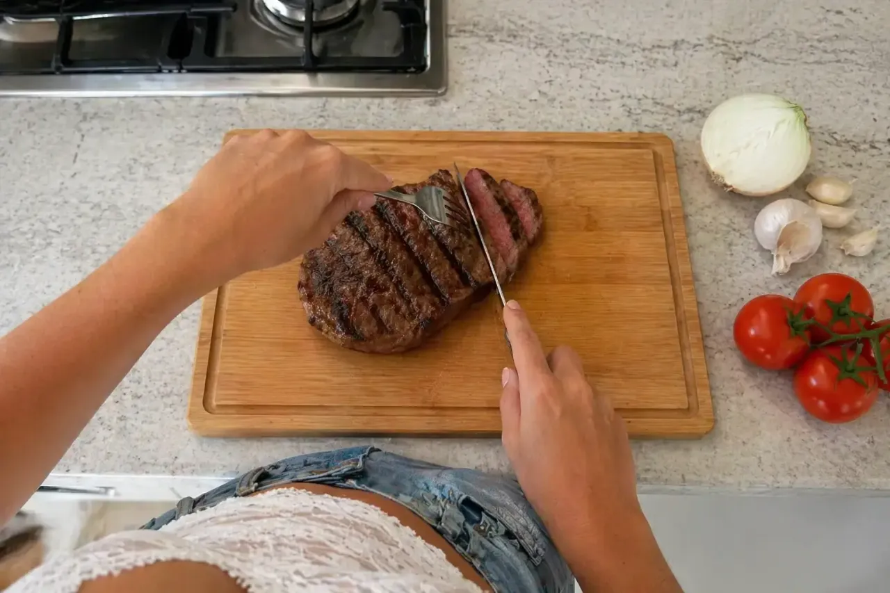 Aansnijden van een gegrilde steak op de houten snijplank, in haar keuken